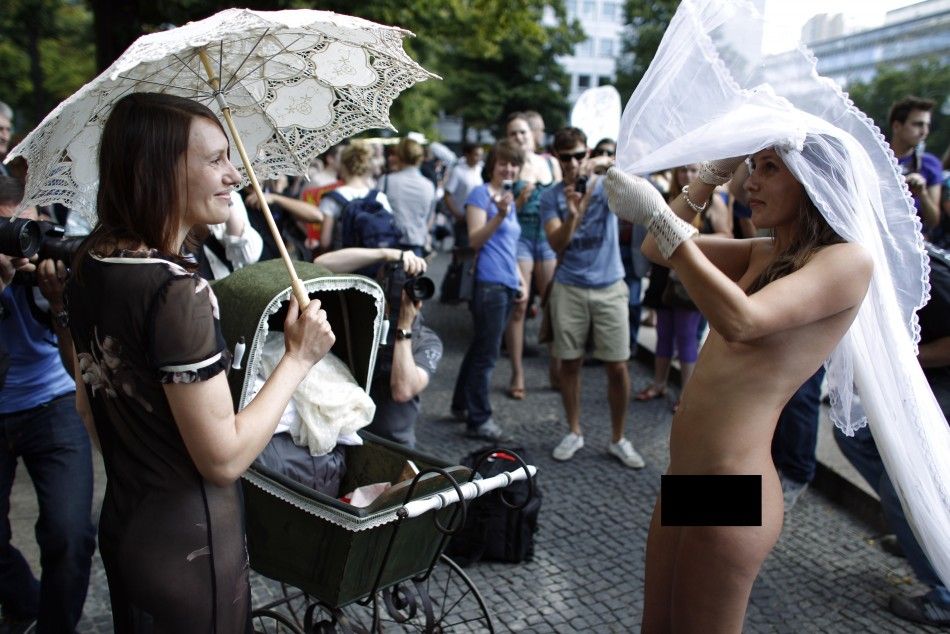 A naked woman puts on a veil during a SlutWalk rally against sexual abuse in central Berlin
