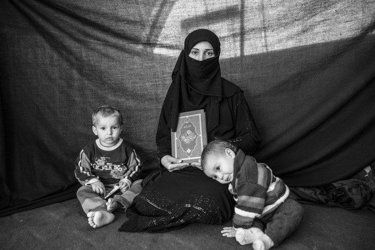 Syrian Refugee Mother With Her Children And Koran