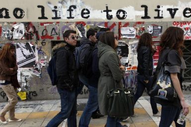 Students walk past graffiti painted on the wall of a building in central Athens March 15, 2012.