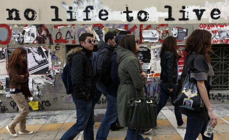 Students walk past graffiti painted on the wall of a building in central Athens March 15, 2012.