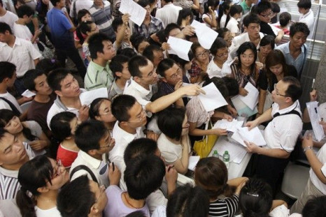 Jobseekers pass their resumes to representatives from Foxconn Technology Group at a job fair in Zhengzhou