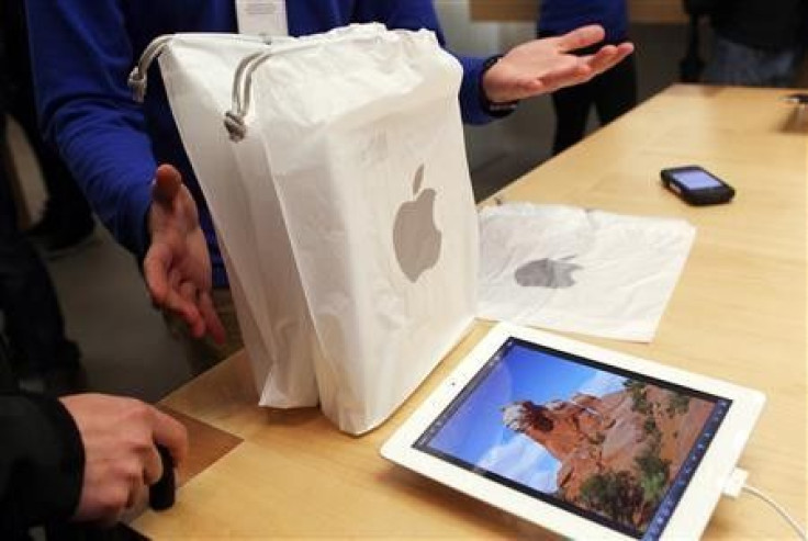 An employee presents purchased new iPads to a customer at the Apple flagship retail store in San Francisco, California in this March 16, 2012, file photo.