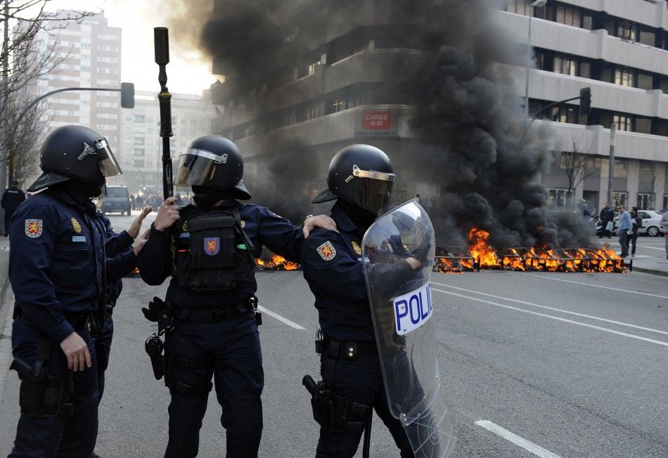 Riot Police stand in front of a burning barricade during Spains general strike in Gijon