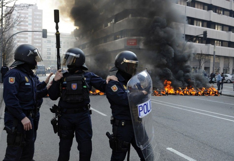 Riot Police stand in front of a burning barricade during Spain's general strike in Gijon