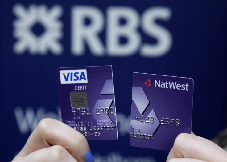 A demonstrator holds up her destroyed NatWest debit card as she stands in front of a branch of the Royal Bank of Scotland in London