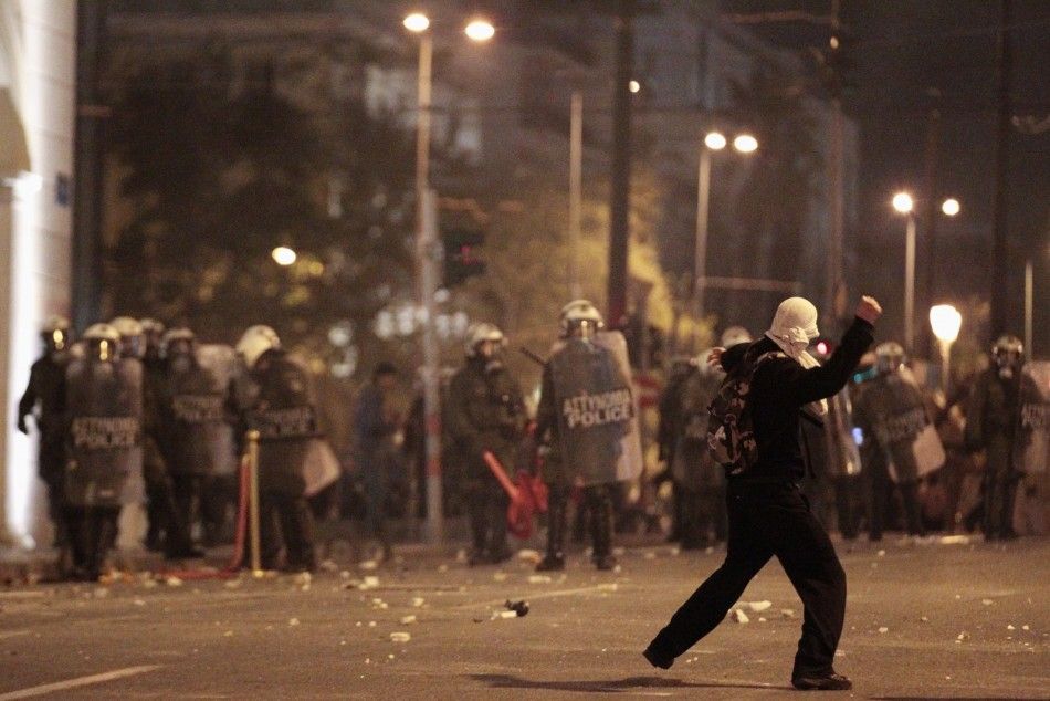 A protester throws a stone at policemen during riots at central Syntagma square in Athens