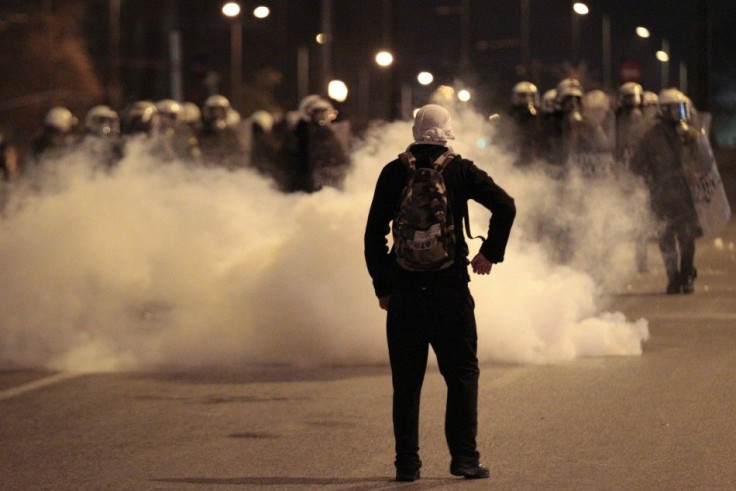 A protester looks at policemen standing behind teargas during riots at central Syntagma square in Athens