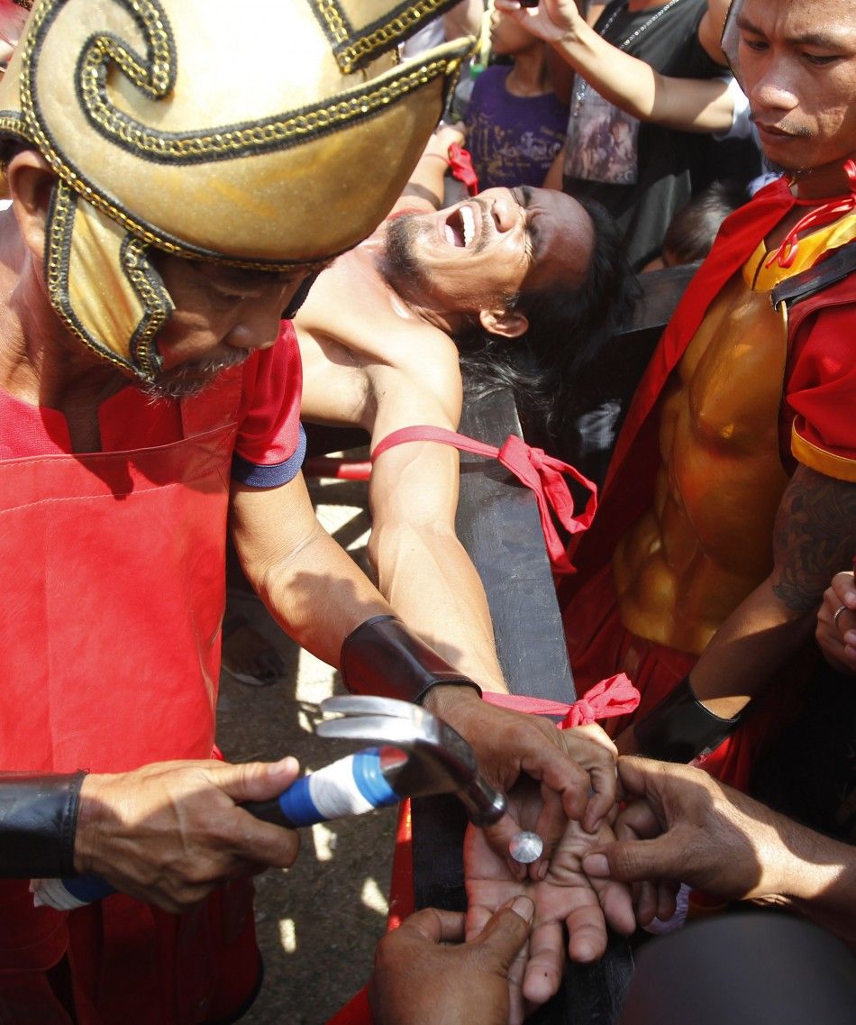 Filipino penitent Gomez grimaces while being nailed to a wooden cross during a reenactment of Jesus Christs crucifixion on Good Friday in Barangay Cutud