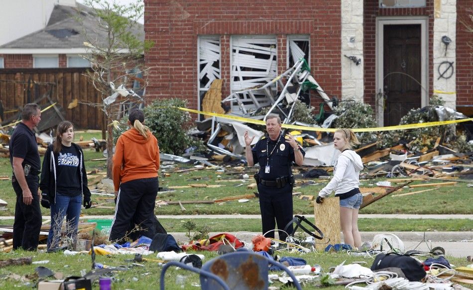 A police officer talks to residents near a damaged house during a cleanup effort in Forney, Texas
