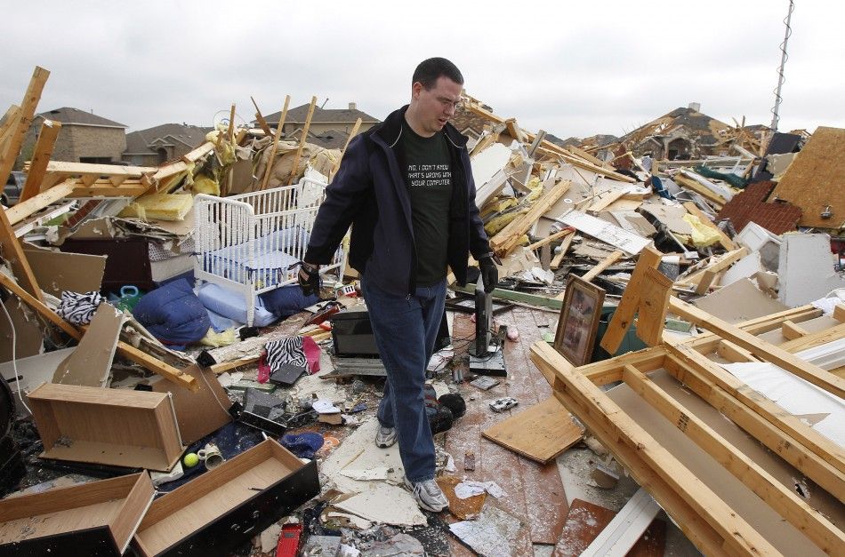 A man walks through the wreckage of a neighbors home during a cleanup effort in Forney, Texas