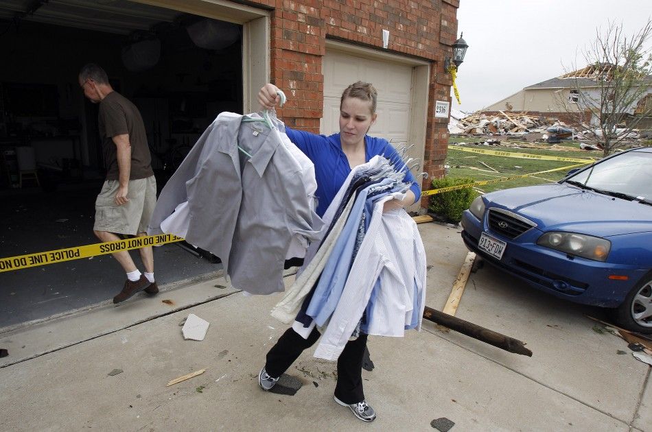 Linda Duy carries clothing out of her parents house during the cleanup effort in Forney