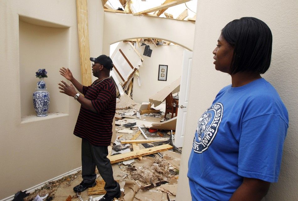 Michael Lynch reaches for a vase that survived the storm as Xyllena Lynch looks on during the cleanup effort after in Forney