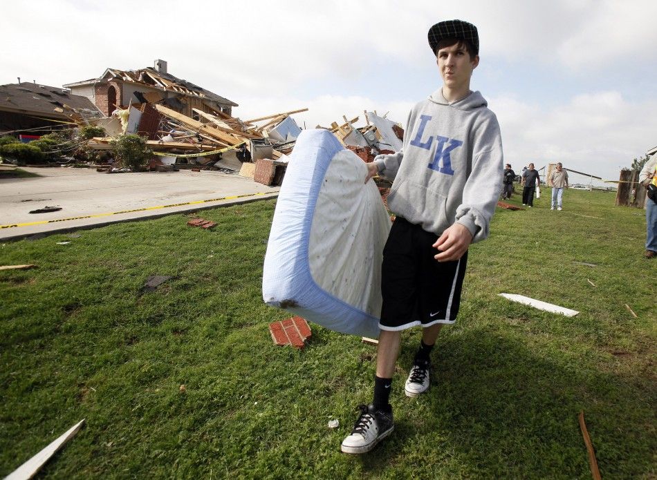 Denver Enochs carries a mattress from the remains of his home during the cleanup effort in Forney 