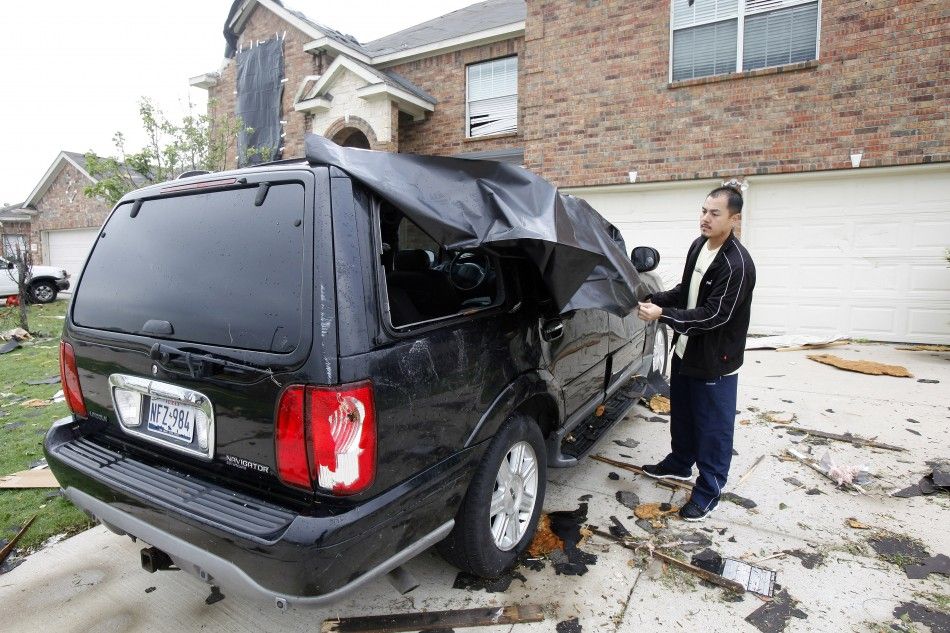 Joe Pham covers his vehicle during the tornado cleanup effort in Forney