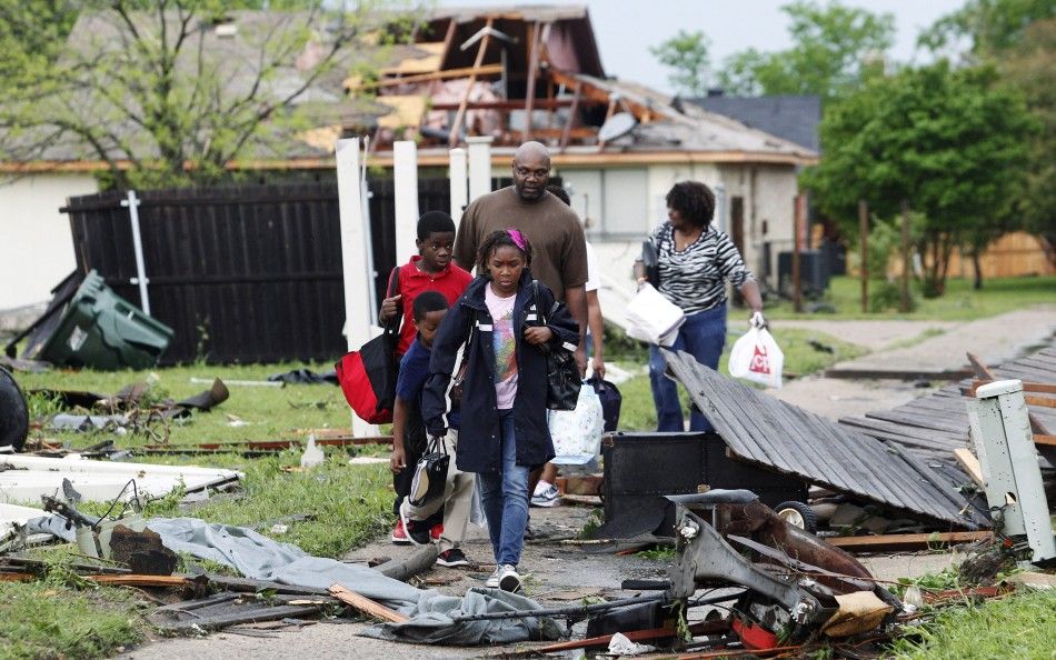 A family walks through the debris after their neighborhood was damaged by a series of tornadoes ripped through the Dallas suburb of Lancaster