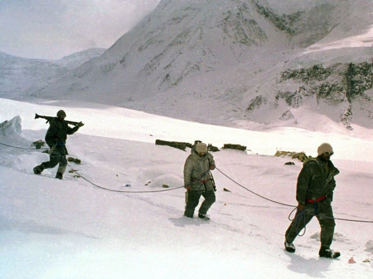 Pakistani soldiers, tied to each other for safety in hostile weather conditions, carry their weapons some time in June 1999 as they cross a snowy field on the Siachen Glacier in Pakistan.