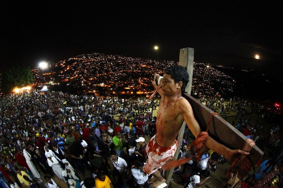 An actor is seen on the cross in a re-enactment of the crucifixion of Jesus Christ on Good Friday in Caracas biggest slum of Petare April 6, 2012. 