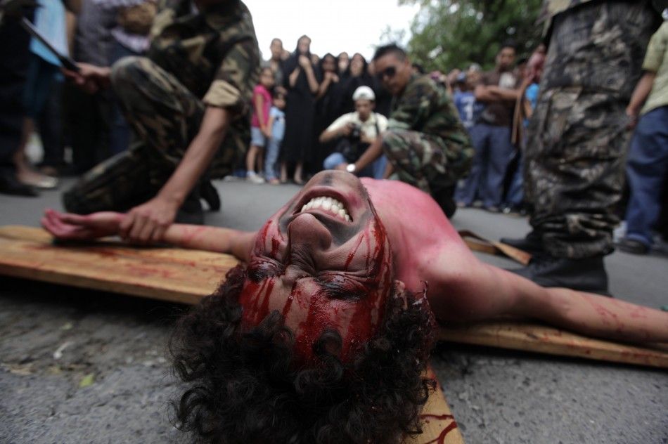 Migrants dressed as U.S. border patrol agents pretend to nail another migrant representing Jesus Christ to the cross in a re-enactment of the crucifixion of Jesus Christ on Good Friday in Saltillo April 6, 2012. 