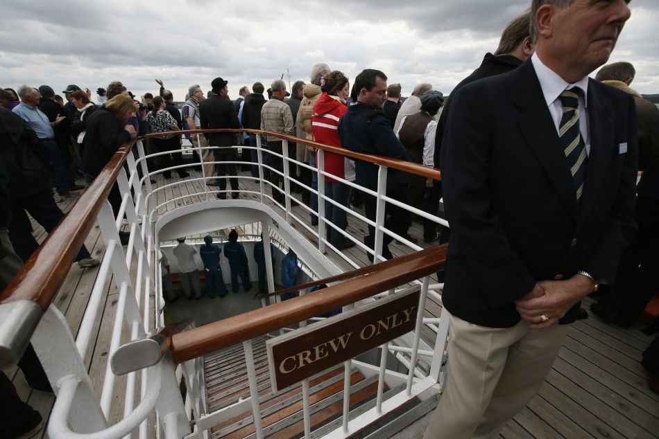 Members of the crew are seen at the deck below partying guests as the Titanic Memorial Cruise leaves port in Southampton