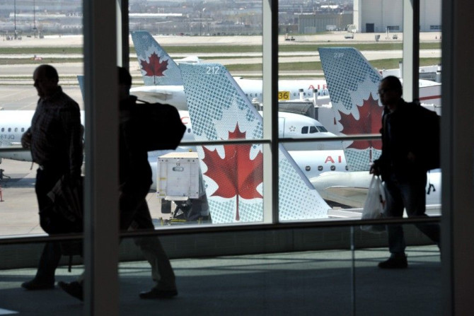 Passengers walk past Air Canada planes on the runway at Pearson International Airport in Toronto.