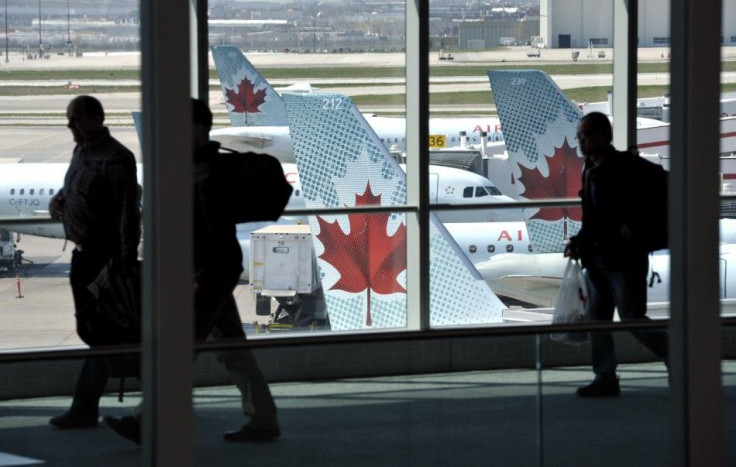 Passengers walk past Air Canada planes on the runway at Pearson International Airport in Toronto.