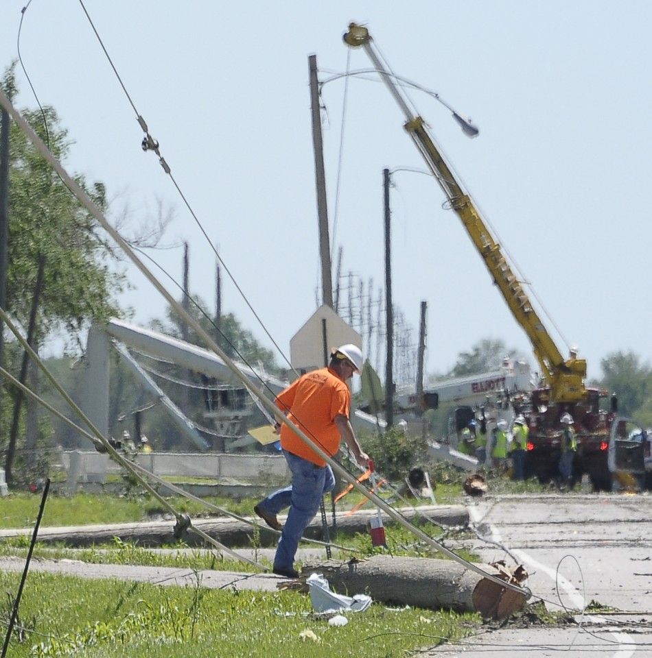 A worker walks near a downed power line caused by tornado damage in the southern area of Wichita, Kansas