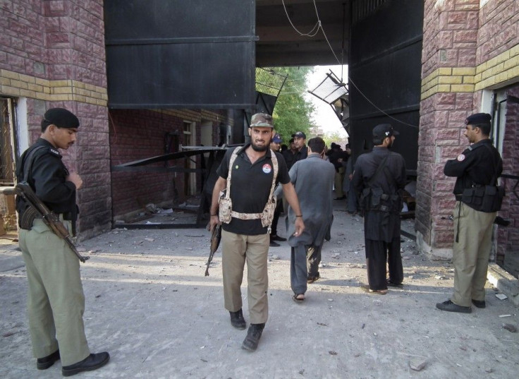 Policemen gather near a damaged jail gate after inmates escaped from the prison in the town of Bannu Pakistan
