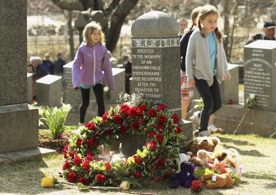 Children walk past the grave of an unknown child from the Titanic sinking at the Fairview Lawn Cemetery in Halifax