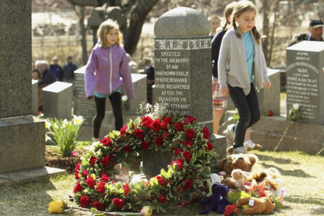 Children walk past the grave of an unknown child from the Titanic sinking at the Fairview Lawn Cemetery in Halifax