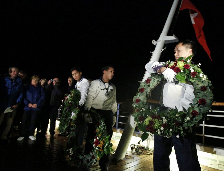 Crew members carry wreaths to be thrown into the sea during a service of remembrance aboard the Titanic Memorial Cruise in the western Atlantic Ocean