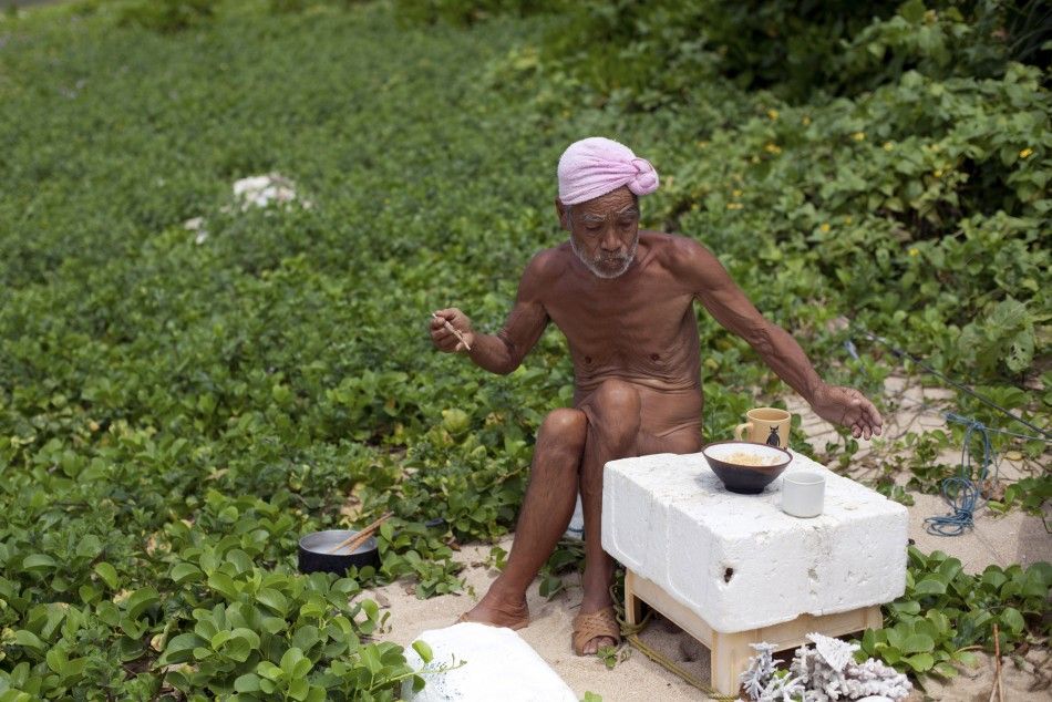 Seventy-six-year-old naked hermit Nagasaki eats a food on Sotobanari island, Okinawa prefecture, Japan