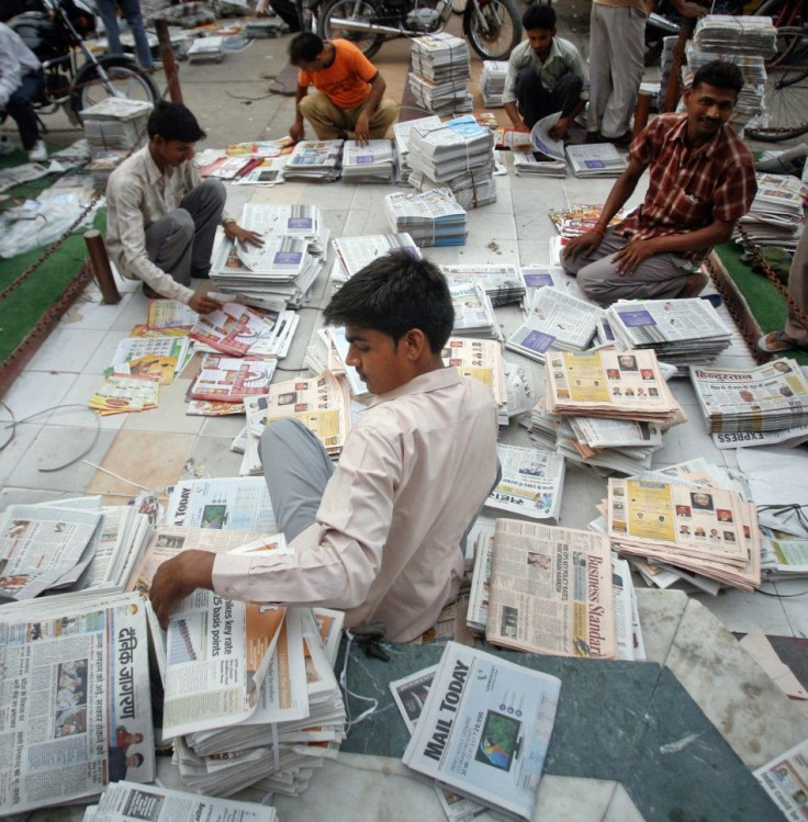 Distributors sort through newspapers before selling them during early hours in Noida.