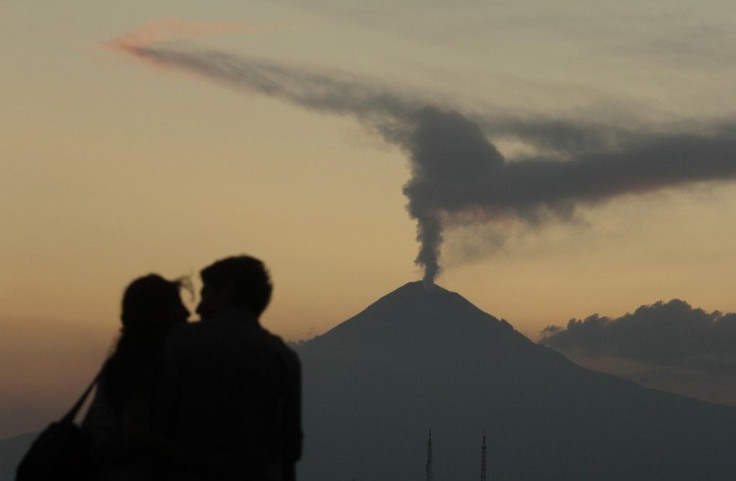 Couple embraces as the Popocatepetl volcano spews a cloud of ash and steam high into the air as seen from Puebla