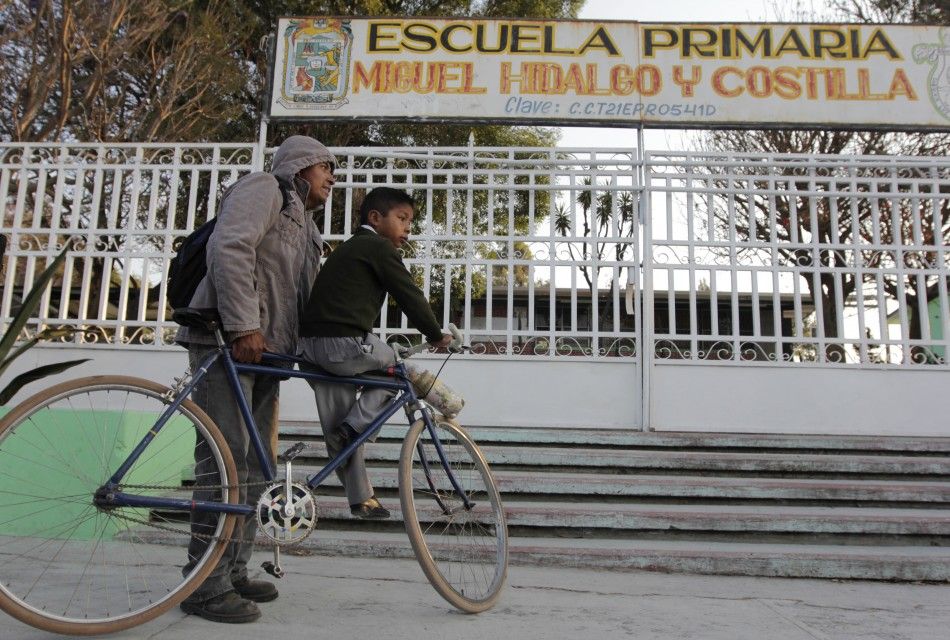 A man and his son stand outside a closed school in San Nicolas de los Ranchos