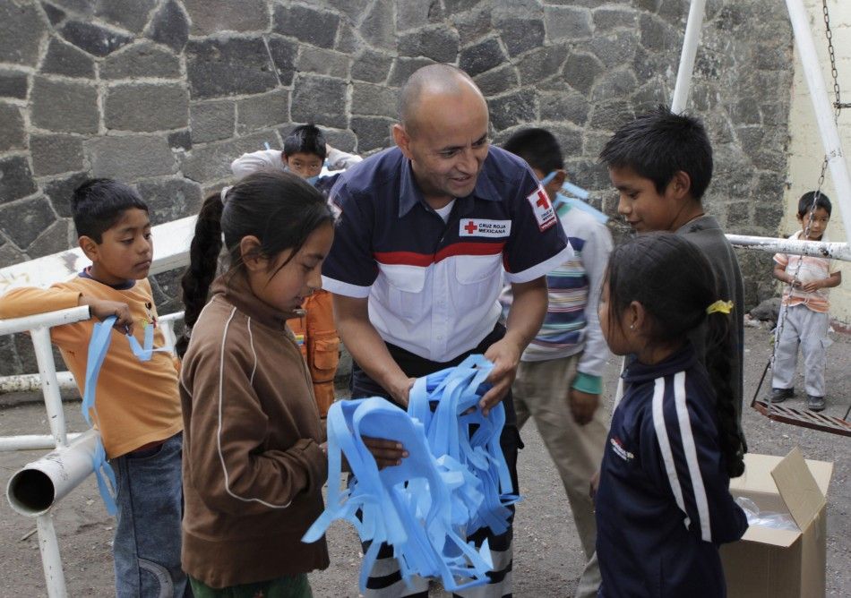 A Red Cross worker hands out surgical masks to children in San Nicolas de los Ranchos