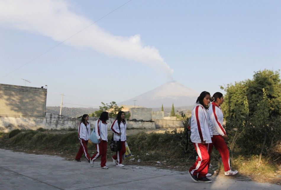 A plume of steam and ash rising from Popocatepetl volcano is seen as school children walk in San Nicolas de los Ranchos