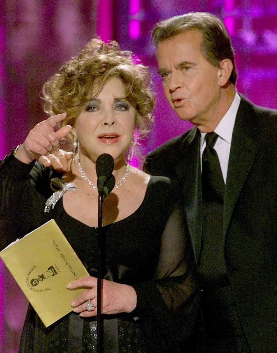 Producer Dick Clark R comes to the aid of Elizabeth Taylor after Taylor lost her place announcing the winner of Best Motion Picture Drama at the 58th Annual Golden Globe Awards January 21, 2001 in Beverly Hills