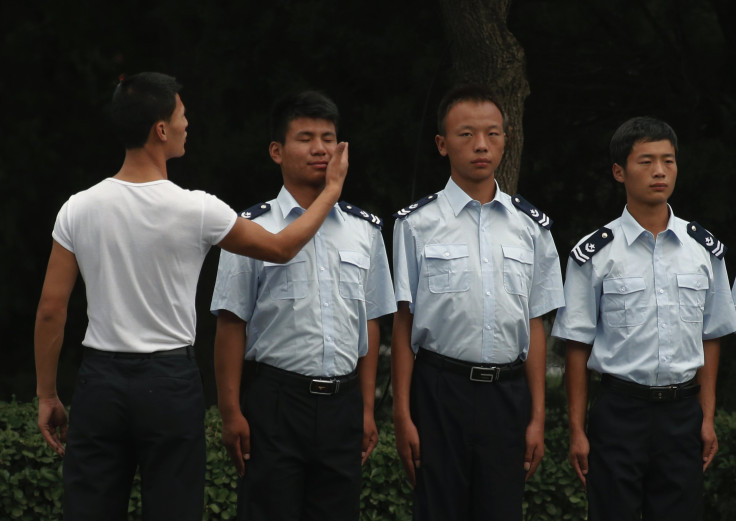 A man slaps the face of a firefighter as he stands in a line with colleagues during an inspection in central Beijing 