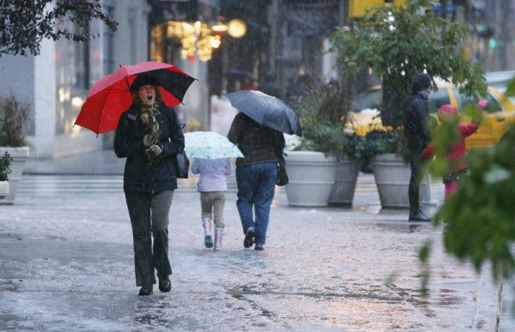 Pedestrians walk through a snow flurry during an early snow storm in New York October 29, 2011. A