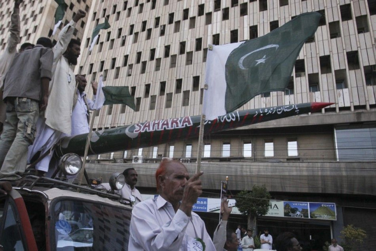 A protestor holds Pakistan&#039;s national flag as others shout slogans while transporting a mock missile during a rally in support of the Pakistan army in Karachi