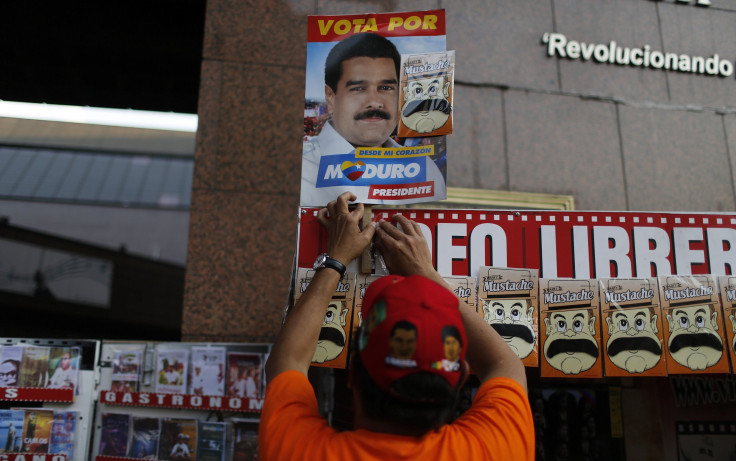 A street vendor arranges a picture of Venezuela's acting President and presidential candidate Nicolas Maduro above a row of fake moustaches in Caracas