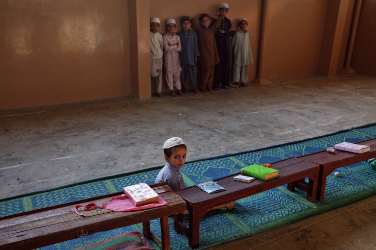 A student sits on floor while others stand beside a wall in a madresa (religious school) on the outskirts of Karachi 