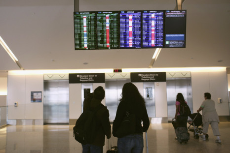 Airline passengers look at a flight status board at San Francisco International Airport in San Francisco