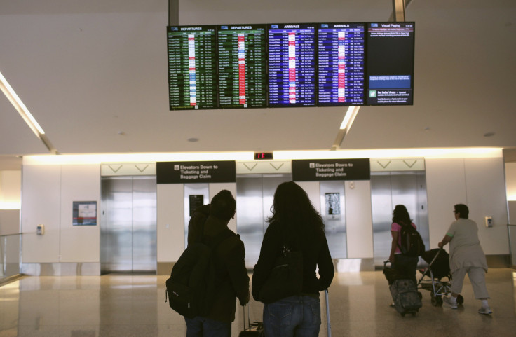 Airline passengers look at a flight status board at San Francisco International Airport in San Francisco