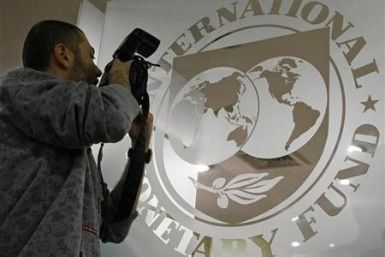 A photographer takes pictures through a glass carrying the International Monetary Fund (IMF) 
