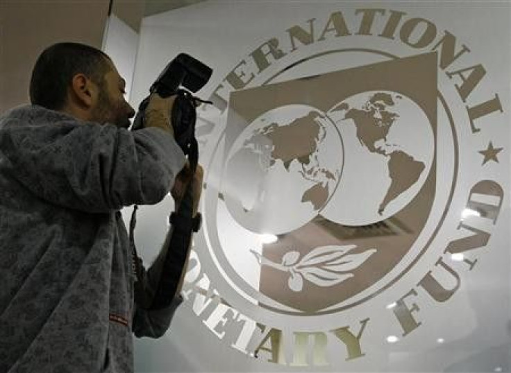 A photographer takes pictures through a glass carrying the International Monetary Fund (IMF) 