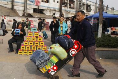 A migrant worker pushes his belongings past a vendor selling foldable stools near Dongguan East station in southern China