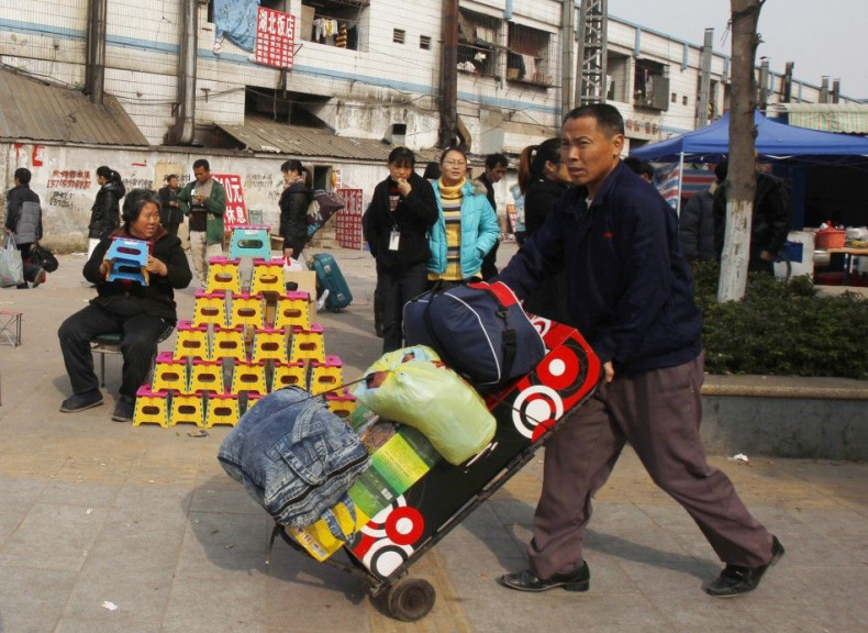 A migrant worker pushes his belongings past a vendor selling foldable stools near Dongguan East station in southern China