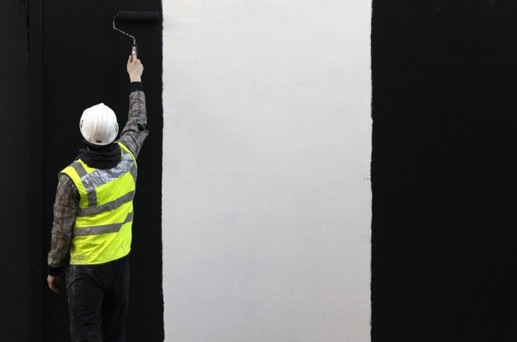 A worker paints a wall on a construction site in London