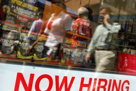Pedestrians walk past a &quot;Now Hiring&quot; sign in the window of a GNC shop in Boston